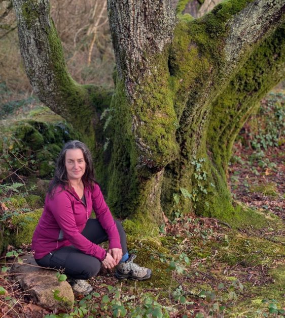 Amanda standing beside an ancient tree in nature